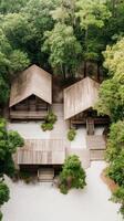 Aerial view of wooden cabins surrounded by lush green forest and white sand landscape. Architecture in nature with peaceful atmosphere. Birdseye of houses photo