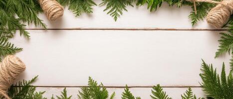 Evergreen branches and twine border white wood surface. Festive frame with copy space. Natural rustic design elements. Holiday theme. Leafy decoration. photo