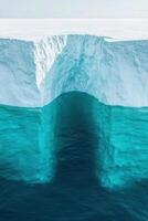 Large iceberg with blue water erosion. Clear sky and bright light highlight frozen scene. Details of cave entrance under the white ice sheet. photo