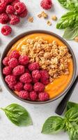 Breakfast bowl. Smoothie with fresh raspberries and granola. Food on a white background. Healthy vegetarian meal. Delicious fruit combination photo