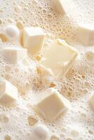 White soap cubes and spheres floating among white foam bubbles. Soft texture close up image of soap suds with neutral background photo