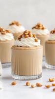 Dessert cups with creamy topping nuts displayed on counter. Delicious vegetarian dessert idea. Delicious peanut desserts for special occasions photo