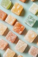 Colorful sugary squares arrange on light blue surface. Vegetarian sweets in pattern. Sweet dessert background with bright tones and uniform light. Delicious snack photo