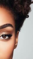 Close view of face. Single eye with long lashes and brown iris. Curly dark hair above. Neutral light background. Part of face. photo