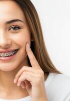 Close-up of smiling teen girl with braces touching her cheek on white background photo