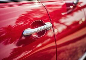 Vintage dark red cherry car detail with polished chrome handle in sunlit setting photo