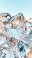 Clear ice cubes pile on light blue surface. Cold crystal blocks stack together. Transparent frozen water glistens. Fresh frosty texture background. photo