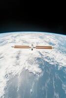 Orbiting structure above Earth. Space station with solar panels faces blue planet and cloudscape. Black space above planet surface showing curvature of planet. photo