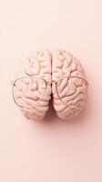 Neural network model with glasses lies on light pink surface. Top view of brain structure used in artificial intelligence algorithms. photo