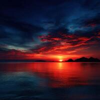 Vibrant sunset over calm waters with silhouetted mountains photo