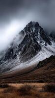 Snow-covered mountain peak under a cloudy sky in twilight photo
