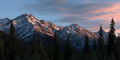 Snow-capped mountains under a pink sky at dusk photo