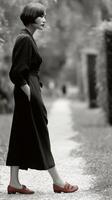 Model in elegant dark dress walking along a garden path photo
