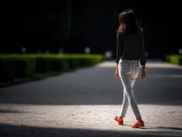 Young woman walking through a well-maintained garden path photo