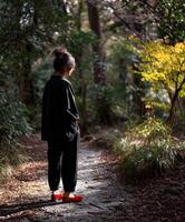 Woman in black attire walking on pathway through forest photo
