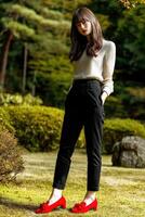 Stylish young woman posing in garden during sunny afternoon photo