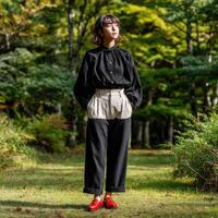 Model in stylish outfit stands amidst lush greenery in autumn photo
