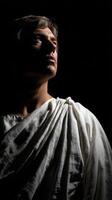 Stoic figure in white drapery gazes upward in dramatic lighting photo