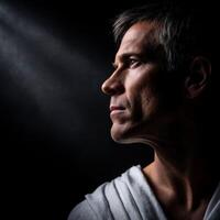 Stoic man in profile illuminated by soft light, expressing deep contemplation photo