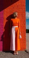 Bright urban fashion featuring a model in vibrant colors against a colorful wall photo