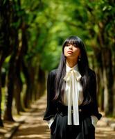 A woman wearing a white shirt and black pants standing in a park photo