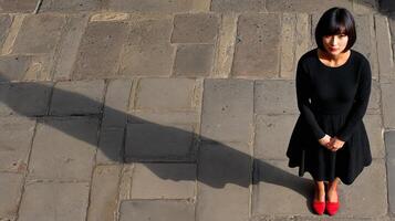 A woman in a black dress standing on a stone floor photo