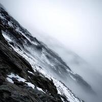 Foggy mountain landscape with steep rocky terrain and snow patches at dawn photo