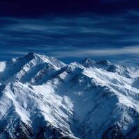 Snow-covered mountain peaks under a dark blue sky at twilight photo