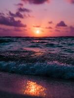 Vibrant sunset over waves at a tranquil beach with reflected colors photo