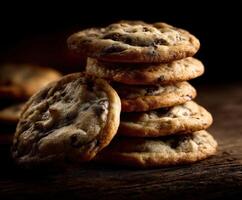 Chocolate chip cookies stacked on a wooden surface with dramatic lighting photo