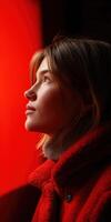 Profile of a woman in a red coat looking at a glowing background photo