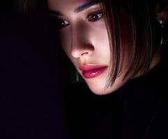 Close-up of a woman focusing intently while using a laptop at night photo