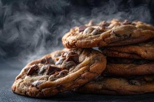 Freshly baked chocolate chip cookies stacked high on a dark surface photo