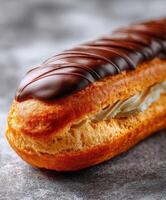 Delicious chocolate eclair on a gray textured surface ready to be enjoyed photo