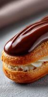 Delicious chocolate eclair with creamy filling presented on a textured surface photo