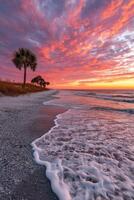 Stunning sunset over the beach with gentle waves and palm trees silhouetted photo