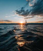 Sailboat navigating tranquil waters at sunset with vibrant sky colors photo