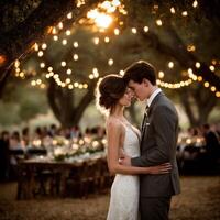 Romantic wedding couple under string lights at sunset photo