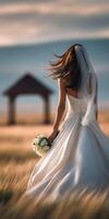 Beautiful bride walking through golden field at sunset photo