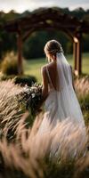 Beautiful bride walking through field with bouquet at sunset photo
