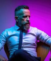 A man with a beard and tie sitting in a chair photo