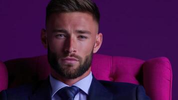 A man in a suit and tie sitting in a purple chair photo