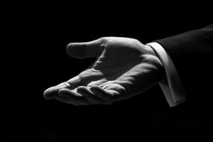 Elegant black-and-white image of an outstretched hand in a formal suit against a dark background photo