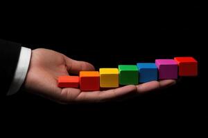 Colorful wooden blocks arranged in a hand against a black background, symbolizing creativity photo