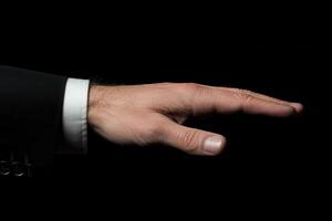 Elegant hand gesture in a formal suit against a dark background, conveying authority and poise photo