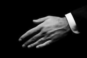 Elegant hand gesture in formal attire against a dark background, symbolizing connection photo