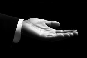 Elegant open hand gesture against a black background, symbolizing invitation or offering photo