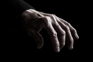 A close-up of an aging hand reaching out against a dark background, symbolizing connection photo