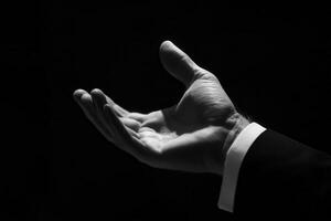 Elegant hand gesture in a dark setting, symbolizing invitation or offering, with contrast photo