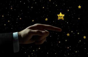 A hand reaching out to touch a golden star against a starry night background photo